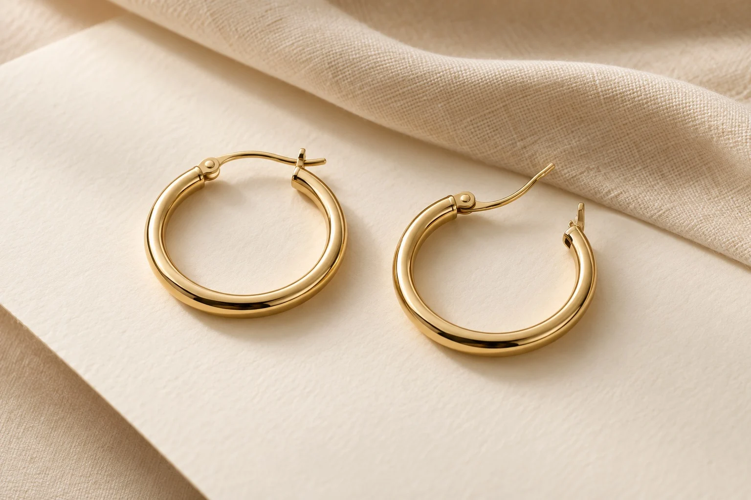 Illustrative studio image of two gold-tone hoop earrings showing their hinged closures